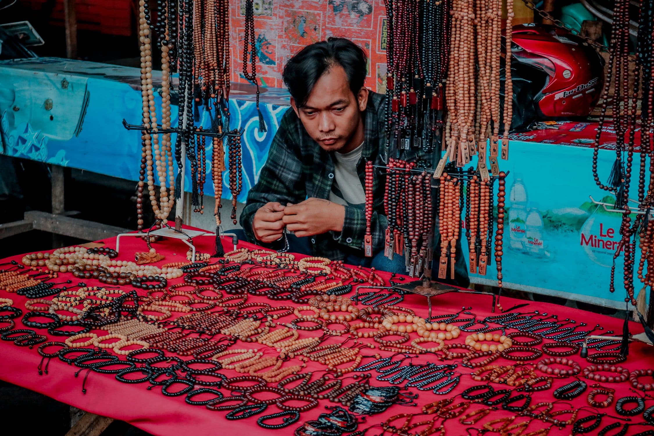 a small handmade market stall table with beaded jewelry displayed and a small handwritten price tag