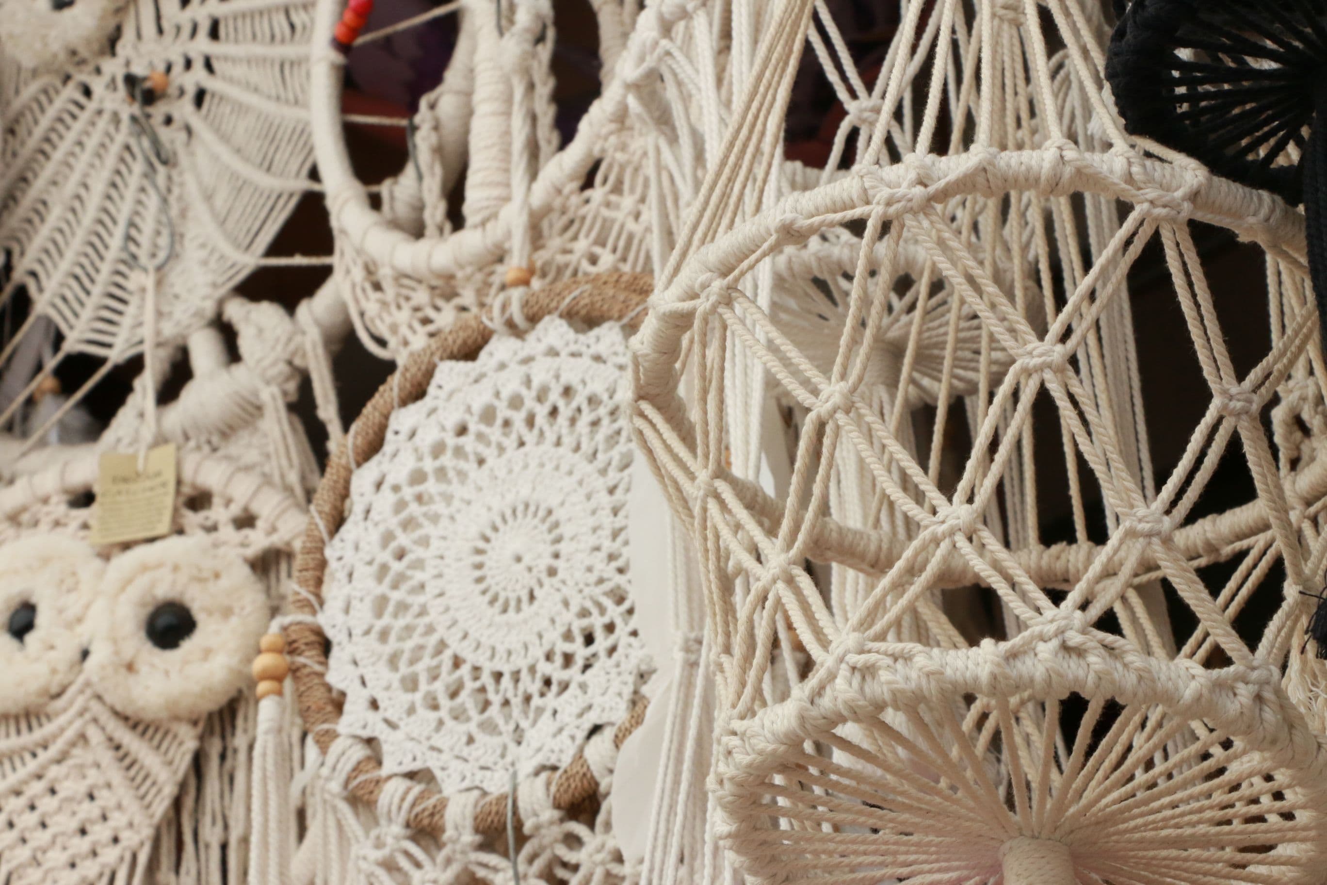 close-up of hands tying macrame knots on a cotton cord plant hanger in progress